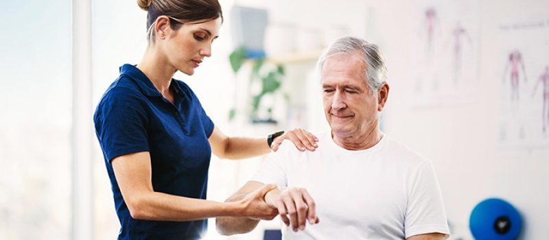 Nurse, patient and physical therapy for elderly care, medical or healthcare support at the clinic. Woman physiotherapist or chiropractor helping mature man in physiotherapy or arm stretching.
